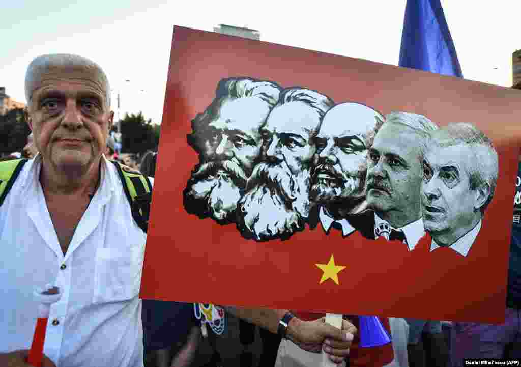 A protester holds a placard depicting Romania&#39;s leftist Social Democratic Party leaders in a lineup of Communist icons.