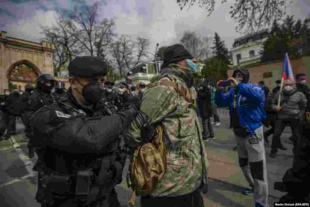 Полиция задерживает контрпротестующего во время акции протеста перед посольством России в Праге 18 апреля после обвинений в том, что российские агенты устроили массовый взрыв боеприпасов в 2014 году