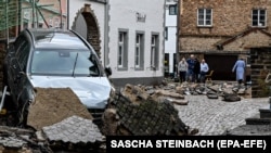  Un drum deteriorat și o mașină după inundațiiile din Bad Muenstereifel / Germania - 15 iulie 2021