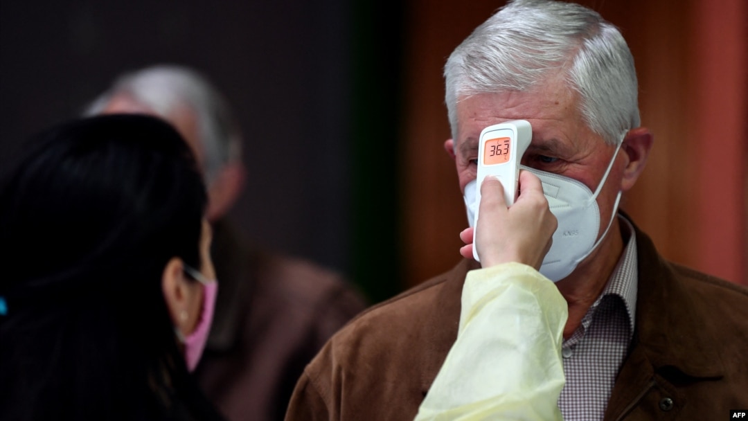 A Bosnian medical worker checks patients' temperatures as they arrive at a vaccination station in Sarajevo.