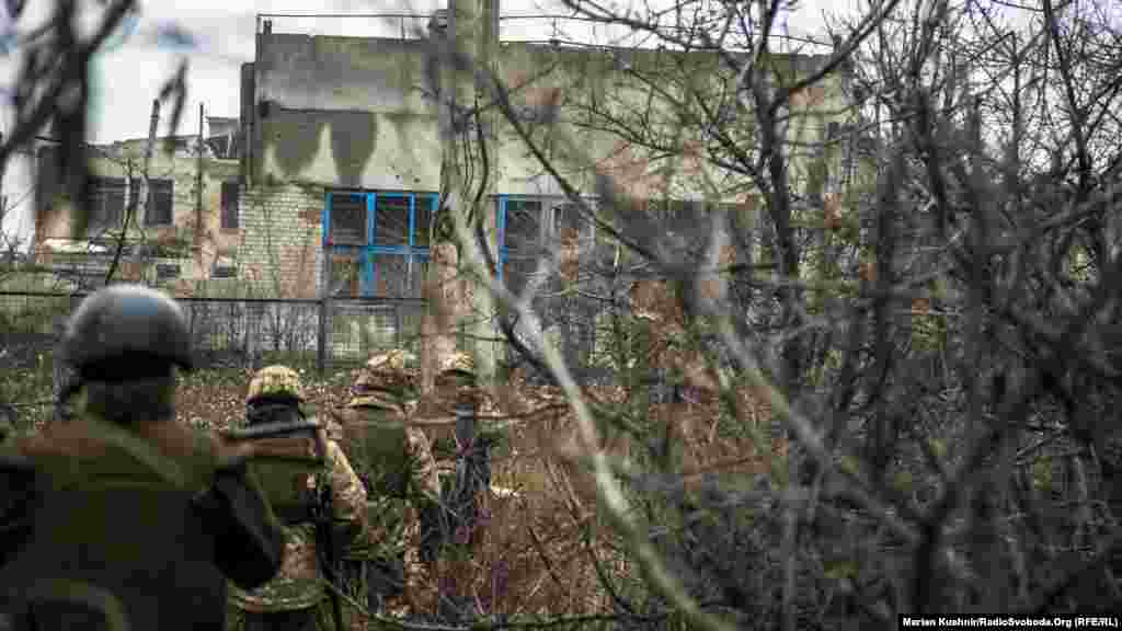 Ukrainian soldiers make their way past damaged buildings in Avdiyivka.&nbsp;