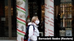 Një grua e veshur me një maskë mbrojtëse për fytyrën ecën në qendër të Budapestit.