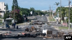 O stradă blocată de resturi de mașini arse în cartierul Magenta din Noumea, teritoriul Franței din Noua Caledonie, pe 18 mai 2024.