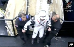 Na ovoj fotografiji napravljenoj iz NASA TV videa, zapovjednika Mike Hopkinsa izvlače iz kapsule SpaceX Dragon nakon što je izvučen iz Meksičkog zaljeva u blizini Floride Panhandle rano u nedjelju, 2. maja 2021.