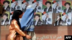 Women walk past posters of President Hamid Karzai in Kabul.