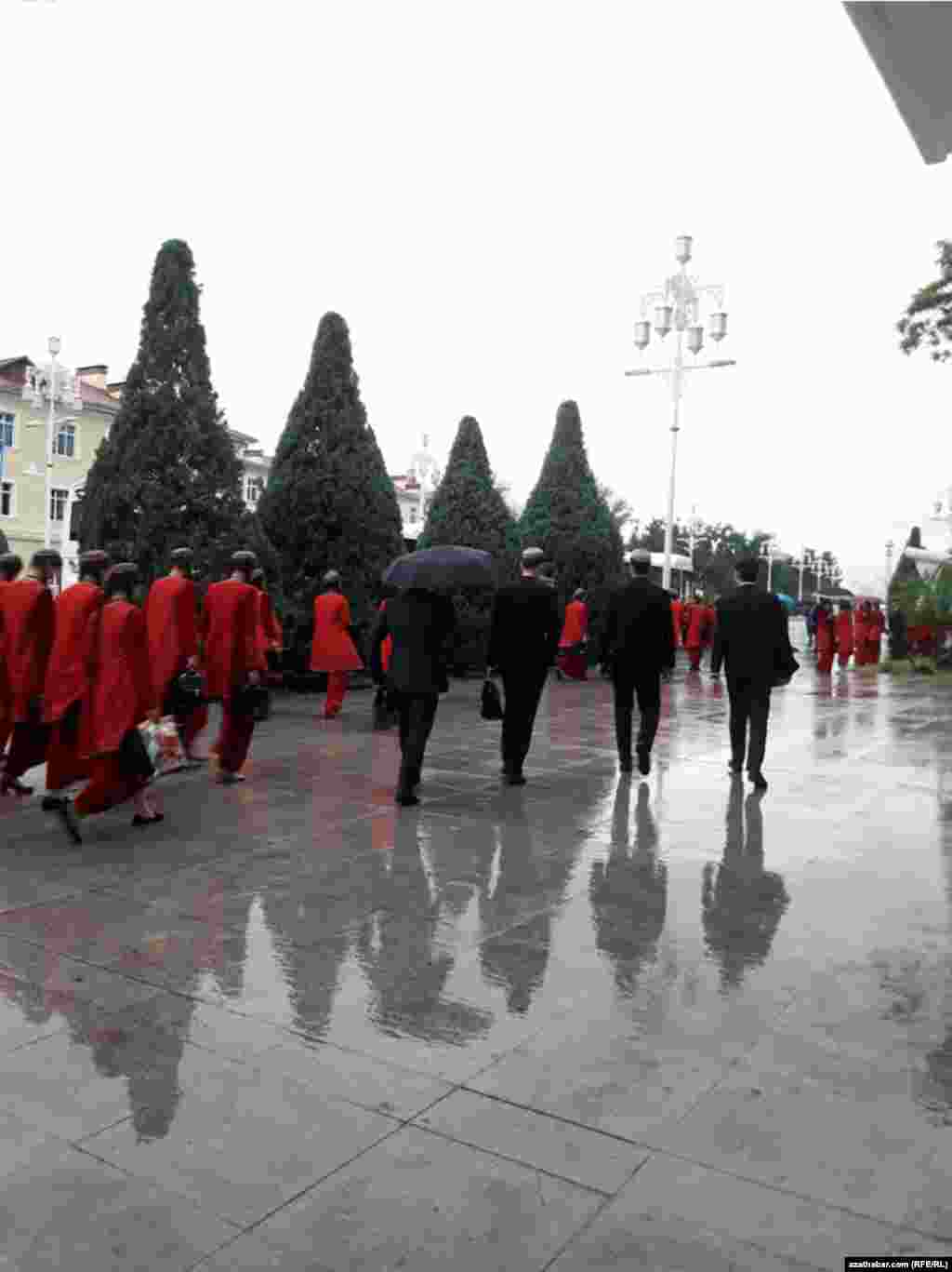 Aşgabat. Ýagýyşly howada milli eşikli, tahýaly okuwa barýan studentler. Aprel, 2020.