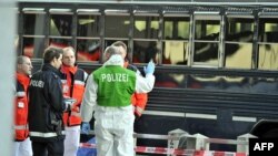 Policajac i hitna pomoć ispred američkog vojnog autobusa nakon napada na aerodromu u Frankfurtu, 2. mart 2011.