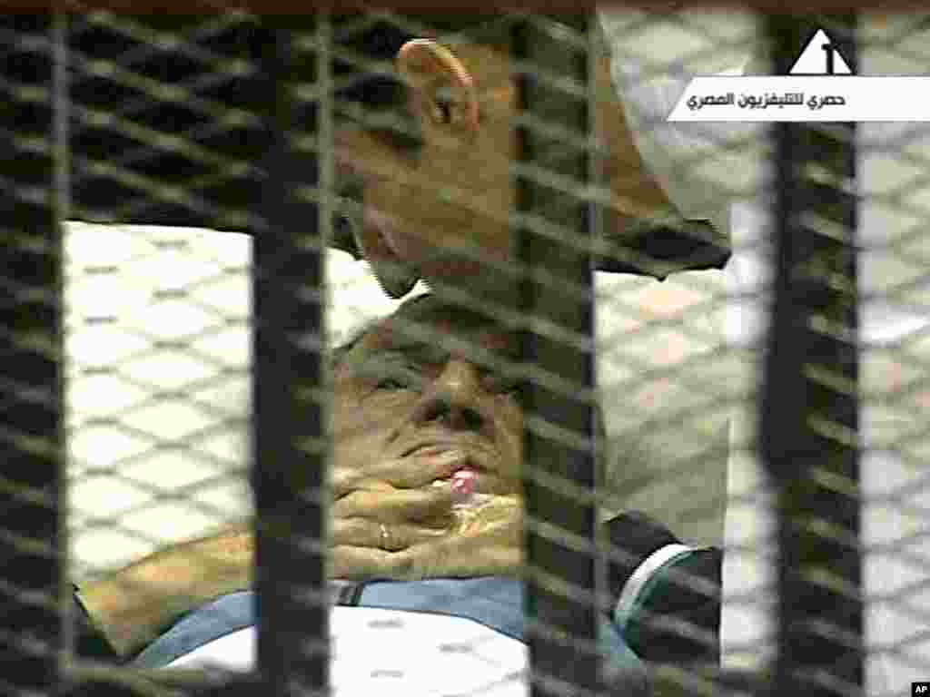 In this video image taken from Egyptian state television, 83-year-old former Egyptian President Hosni Mubarak is kissed by his son Alaa as he lies on a bed within a cage at the court building in Cairo. Mubarak returned to a Cairo court on a stretcher for another session of his trial on charges of corruption and complicity in killing protesters during Egypt's uprising.