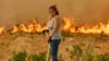 O femeie încearcă să stingă focul, cu un furtun, în timpul unui incendiu forestier în Santa Baia De Montes, nord-vestul Spaniei, 14 august 2025.