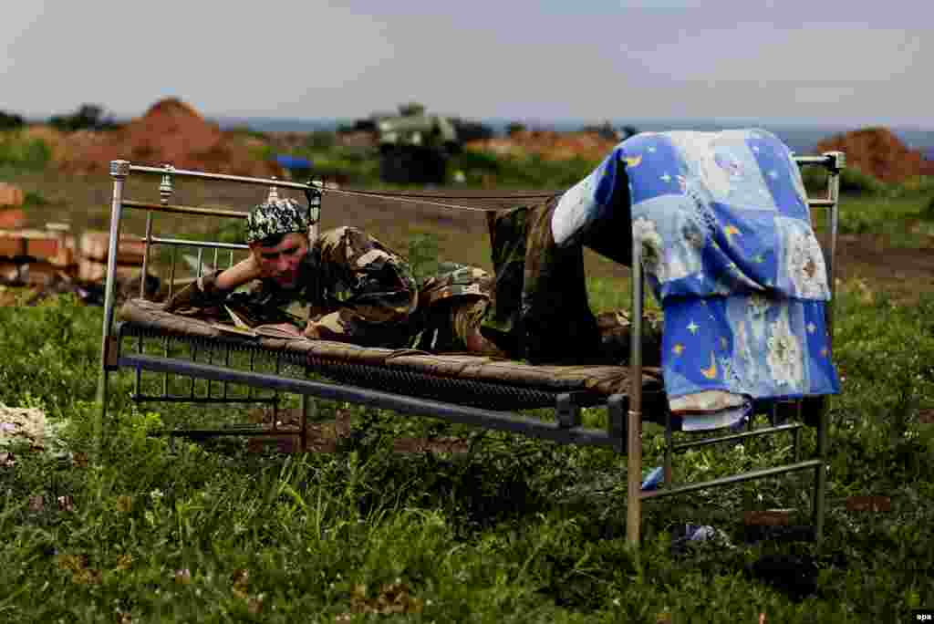 A Ukrainian serviceman from the Kyiv-2 volunteers battalion reads a book while his unit remains in position near the village of Krymske in the eastern Luhansk region. (epa/Ivan Boberskyy)