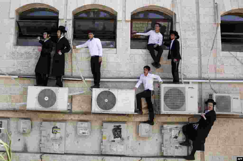 Israeli ultra-Orthodox Jews watch as police work at the scene after a Palestinian man rammed an excavator into a bus in Jerusalem on August 4, killing one person and slightly injuring five others. (AFP/Gali Tibbon)