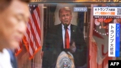 Trampın İranla müharibə ilə bağlı xalqa canlı müraciətini göstərən televiziya ekranının yanından keçən Tokio sakini.