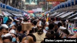 Maszkot és arcvédőt viselő filippínók sétálnak egy utcai piacon a Fülöp-szigeteki Manilában 2020. december 3-án