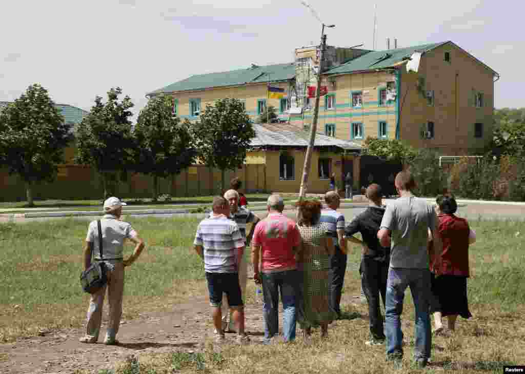 Місцеві мешканці дивлятиься на пошкодження, які отримали будинки Луганського прикордонного загону під час нападу проросійських бойовиків 2 червня. Фото: Луганськ, 3 червня 2014 року