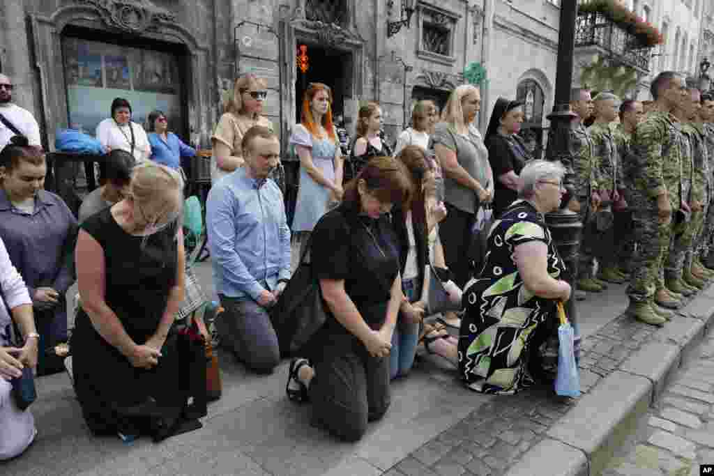 People kneel in Lviv as they pay their respects to the 12 Ukrainian soldiers who died in Russian captivity.