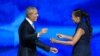 Former US President Barack Obama reaches out to embrace his wife and former First Lady, Michelle Obama, after she introduced him to the stage on the second day of the Democratic National Convention (DNC) at the United Center in Chicago, Illinois, on Augus