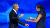 Former US President Barack Obama reaches out to embrace his wife and former First Lady, Michelle Obama, after she introduced him to the stage on the second day of the Democratic National Convention (DNC) at the United Center in Chicago, Illinois, on Augus