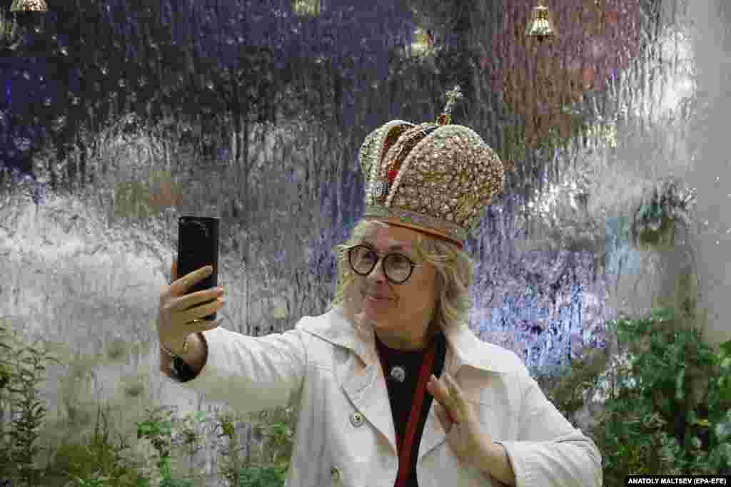 A woman poses with a Russian Imperial crown at an exhibition stand at the 28th St. Petersburg International Economic Forum.