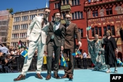Grupul finlandez KAJ reprezentând Suedia cu piesa „Bara Bada Bastu” pășește pe covorul turcoaz de lângă Primăria din Basel în timpul ceremoniei de deschidere a Concursului Eurovision 2025 din Basel, pe 11 mai 2025