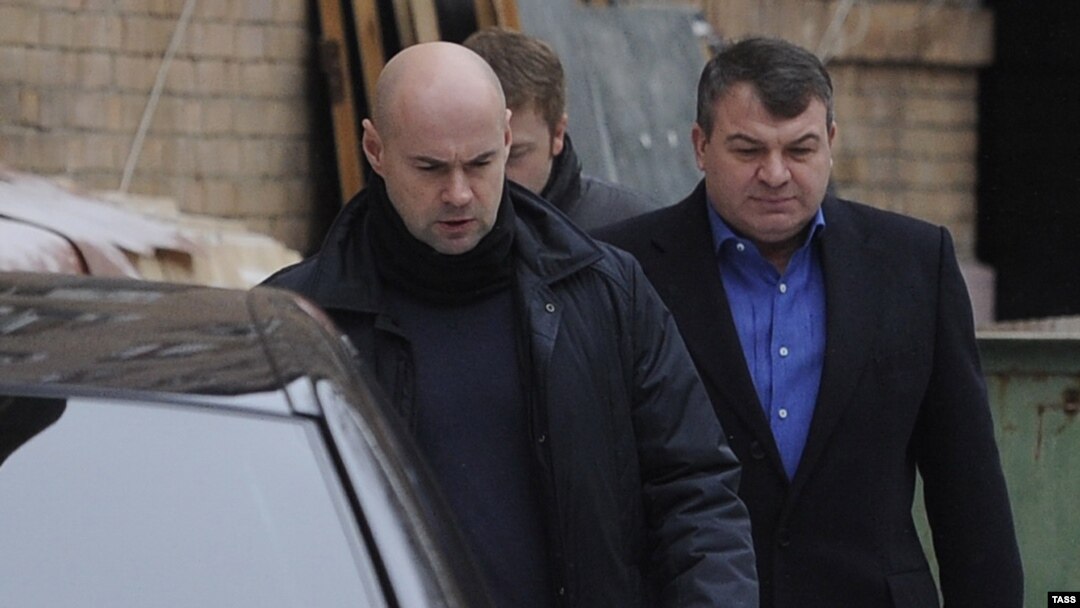Former Defense Minister Anatoly Serdyukov (right) arrives by a back entrance for questioning by investigators in Moscow in December 2013.