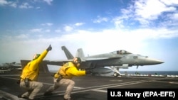 Lt. Nicholas Miller, from Spring, Texas, and Lt. Sean Ryan, from Gautier, Mississippi, launch an F/A-18E Super Hornet from the 'Pukin' Dogs' of Strike Fighter Squadron (VFA) 143 on the flight deck of the Nimitz-class aircraft carrier USS Abraham Lincoln. File phorto