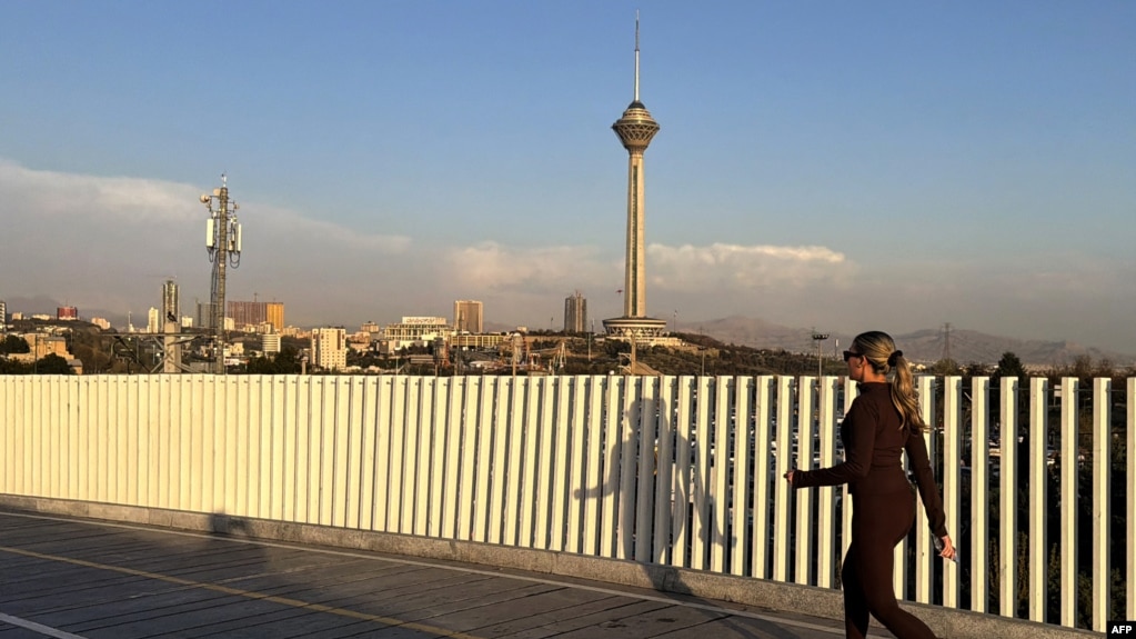 یک زن جوان ایرانی در پارک پردیسان تهران در حال دویدن، در حالی که برج میلاد از دور پیداست (۱۶ فروردین ۱۴۰۵)