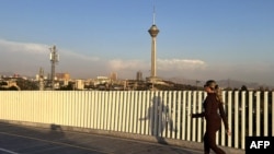 یک زن جوان ایرانی در پارک پردیسان تهران در حال دویدن، در حالی که برج میلاد از دور پیداست (۱۶ فروردین ۱۴۰۵)