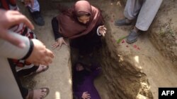 FILE: Afghan civil society activist women weep and lie on the grave of Afghan woman Farkhunda, 27, who was lynched by an angry mob, at the cemetery in central Kabul in March 2015.