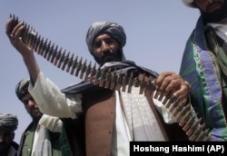 Un fost taliban ține o centură de muniție în timpul unei ceremonii de predare a armelor din Herat, Afganistan, 26 aprilie 2012. Aproximativ 10 foști talibani din provincia Herat și-au predat armele în cadrul unui program de reconciliere a păcii.