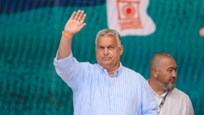 Облечен небрежно в риза на сини и бели райета с