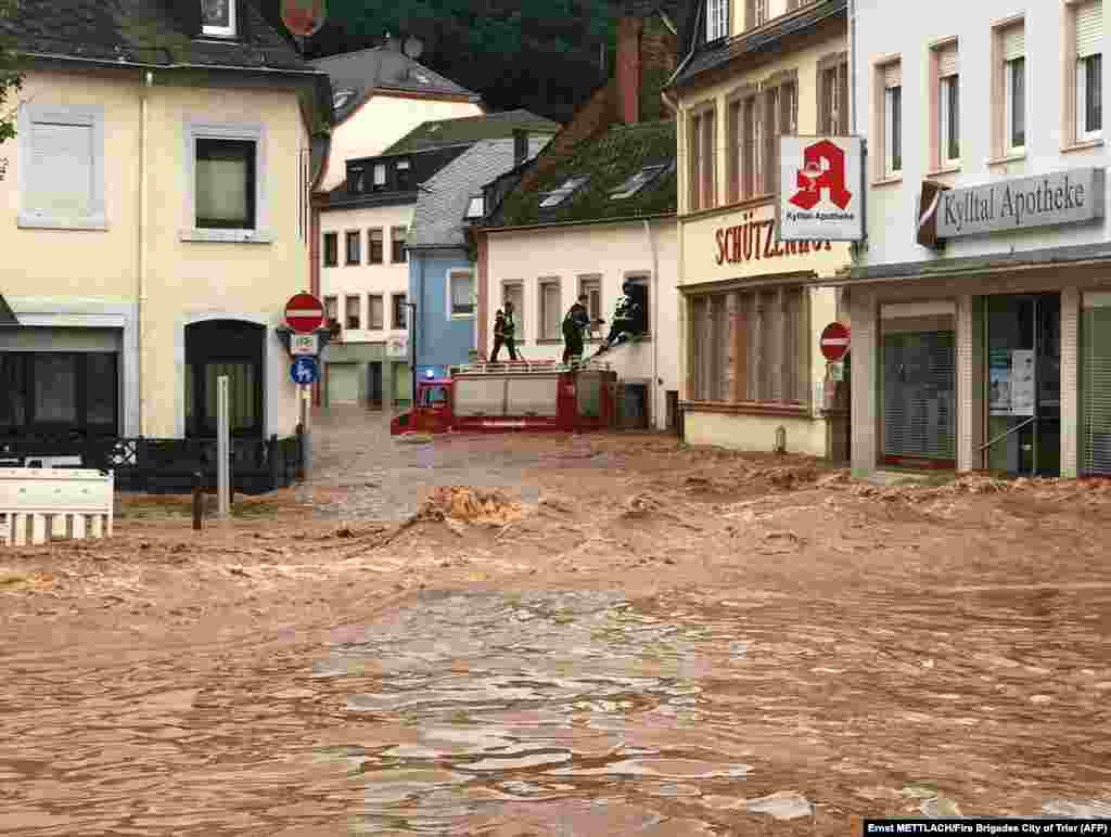 Пожарные с крыши машины забираются в затопленный дом в районе Эранг в Трире, Германия, 15 июля 2021 года