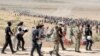 Turkish policemen and soldiers walk past Syrian Kurds waiting behind the border fence to cross into Turkey near the southeastern town of Suruc on September 19.