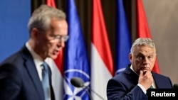 Hungarian Prime Minister Viktor Orban (right) listens as NATO Secretary-General Jens Stoltenberg speaks at a press conference in Budapest on June 12.