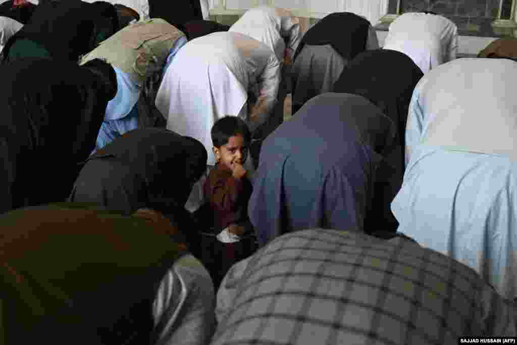 Ребенок наблюдает за совершающими молитву в мечети в Кабуле, Афганистан