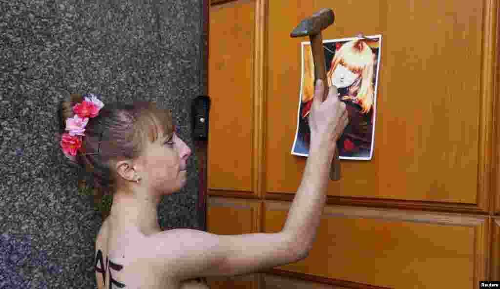 An activist from the women&#39;s rights group Femen nails a photo of her sister to a door as she protests against her kidnapping outside the Ukrainian Security Service (SBU) headquarters in Kyiv. (Reuters/Valentyn Ogirenko)