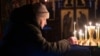 A woman lights a candle during an early celebration of the Epiphany in an Orthodox church in the frontline town of Lyman in the Donetsk region on January 18. 