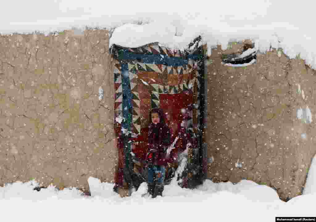 An internally displaced Afghan girl stands at the door of her shelter during a snowfall in Kabul. (Reuters/Mohammad Ismail)