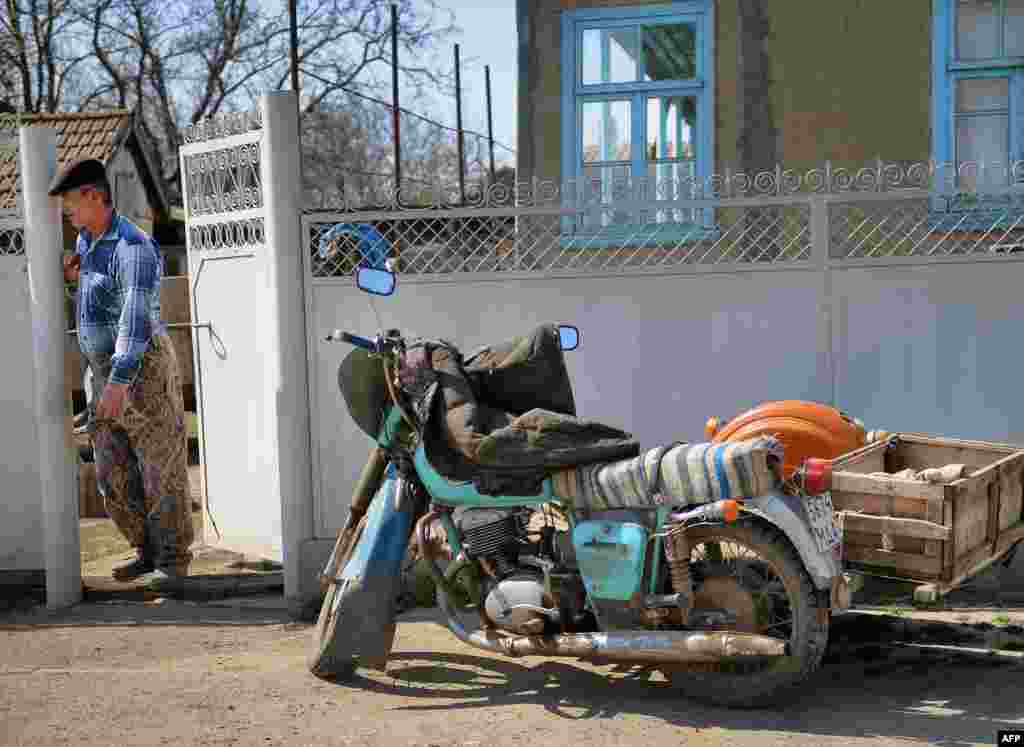 A man stands near his Soviet-era motorcycle.