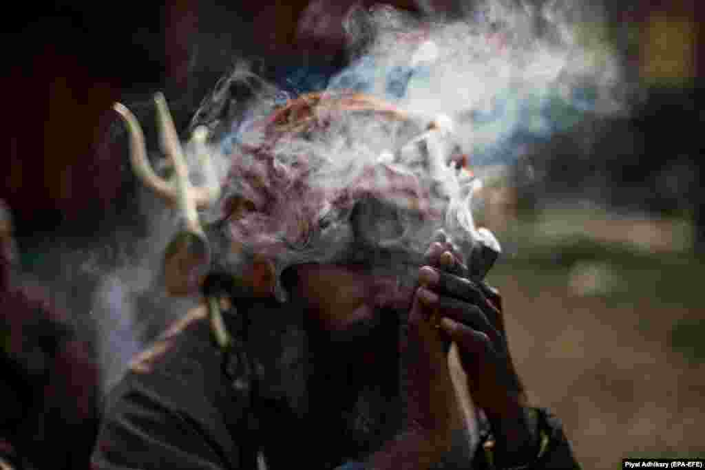 An Indian monk smokes at Babughat transit camp ahead of Ganga Sagar annual Sikh fair in Kolkata. (epa-EFE/Piyal Adhikary)