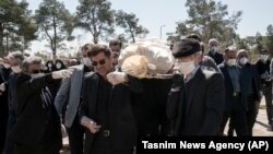 Mourners wearing face masks and gloves carry the body of former politburo official in the Revolutionary Guard Farzad Tazari, who died Monday after a battle with coronavirus in Tehran, March 10, 2020