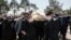 Mourners wearing face masks and gloves carry the body of former politburo official in the Revolutionary Guard Farzad Tazari, who died Monday after a battle with coronavirus in Tehran, March 10, 2020