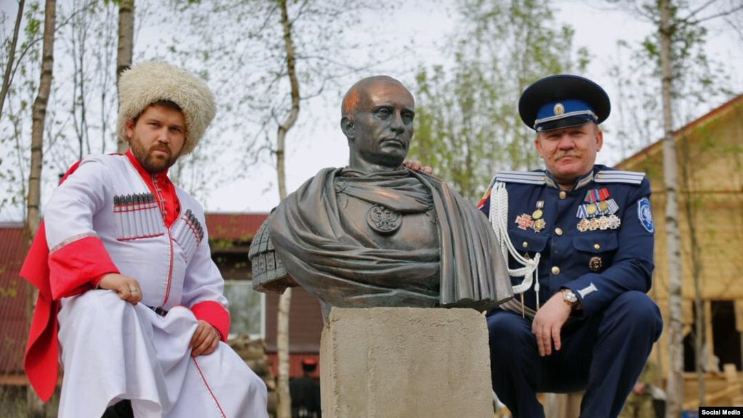 Cossacks pose next to a bust of Vladimir Putin in the guise of a ROman emperor. 