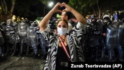 A woman shows a heart standing in front of riot police during a protest against the so-called Russian law near the Parliament building in Tbilisi on Wednesday, May 1. Overnight, police dispersed water cannons and tear gas against protesters.
