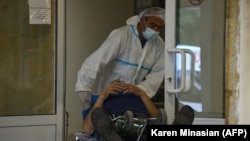 ARMENIA -- A medical worker wearing protective equipment moves a patient into the Grigor Lusavorich Medical Centre in Yerevan, June 9, 2020