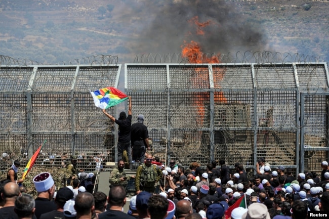 Друзы стоят по обе стороны фактической границы между Израилем и Сирией в разгар конфликта в друзских районах Сирии. Мадждаль-Шамс, рядом с Голанскими высотами. 16 июля 2025 года