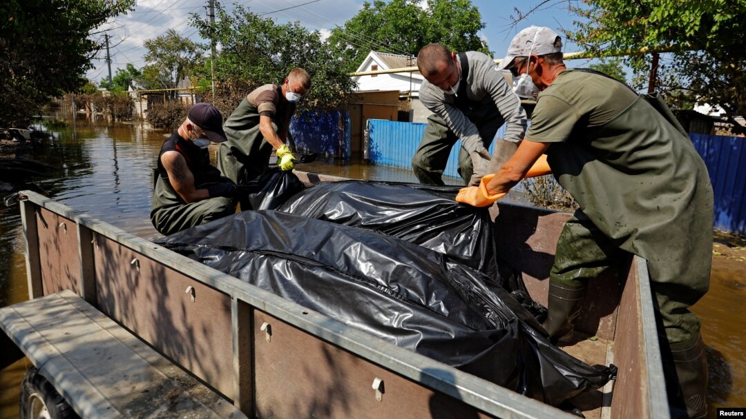 Voluntarii încarcă saci cu cadavre recuperate pe 16 iunie din casele inundate, după ce apele s-au retras în urma ruperii barajului Kahovka