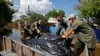 Волонтери і муніципальні працівники складають мішки з тілами загиблих внаслідок повені в окупованій Голій Пристані на Херсонщині, 16 червня 2023 року