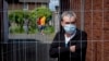 A Romanian worker stands behind a fence that was set up at the entrance of housing for Romania slaughterhouse workers in Rosendahl, Germany, on May 12.