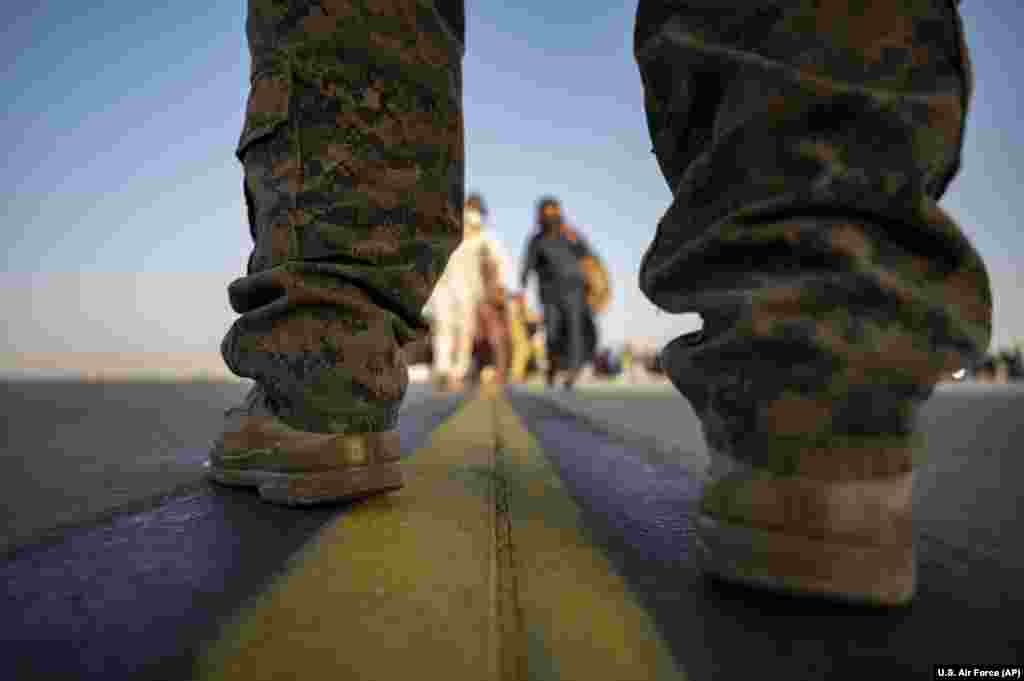 Морской пехотинец США обеспечивает безопасность эвакуированных, садящихся на транспортный самолет США, в международном аэропорту имени Хамида Карзая в Кабуле, Афганистан