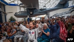 Oamenii sărbătoresc întoarcerea cu bine a misiunii Artemis II la Muzeul Aviației și Spațiului din San Diego.